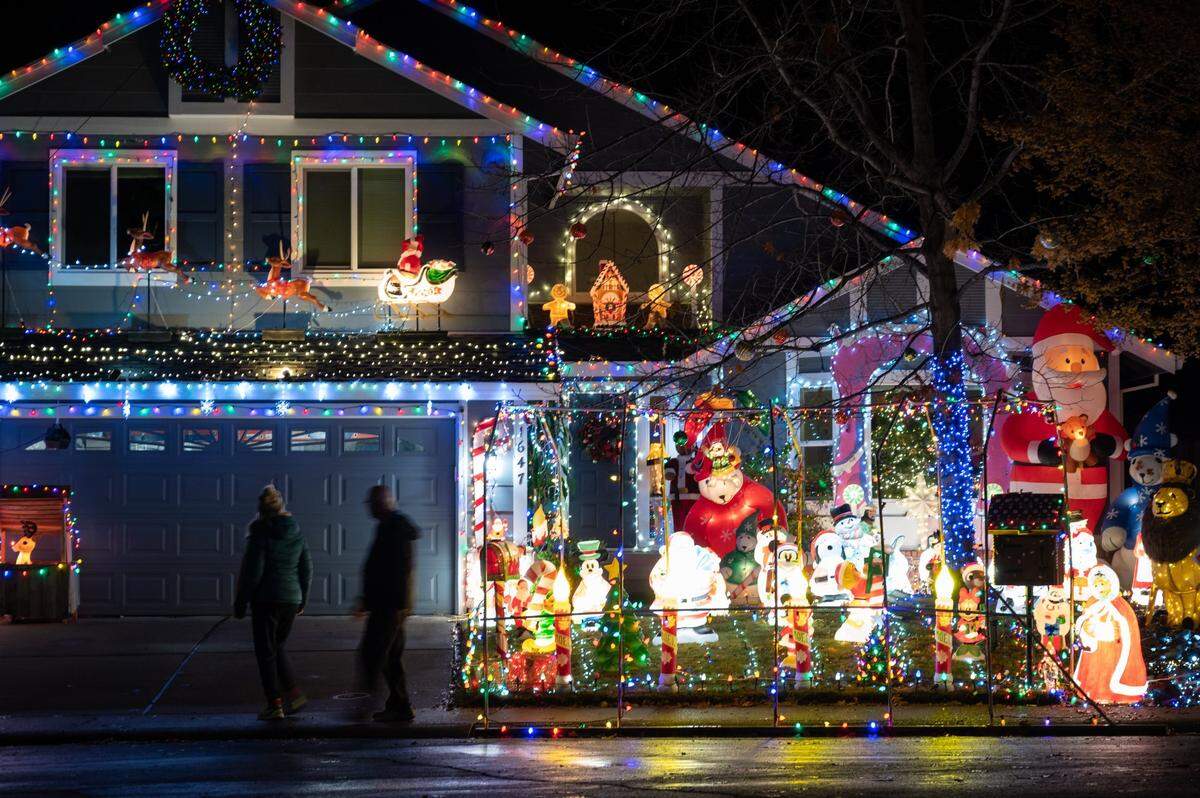 Laurie Van Winkle, left, and her husband Mark take a walk in their neighborhood to look at the Christmas light display at 1647 Alnwick Drive in Roseville on Monday. The house features more than 65 blow molds, a walk in Santa’s workshop, gingerbread house little library and more than 10,000 lights.