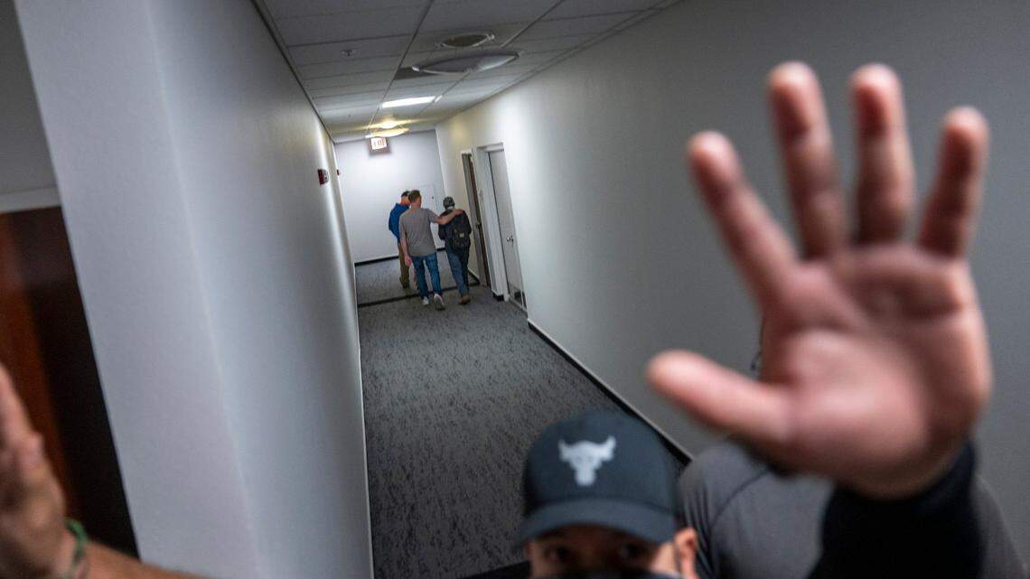A man attempts to block photographs being taken of an individual being led away by federal authorities after appearing in immigration court on Thursday in the John E. Moss federal building in downtown Sacramento.