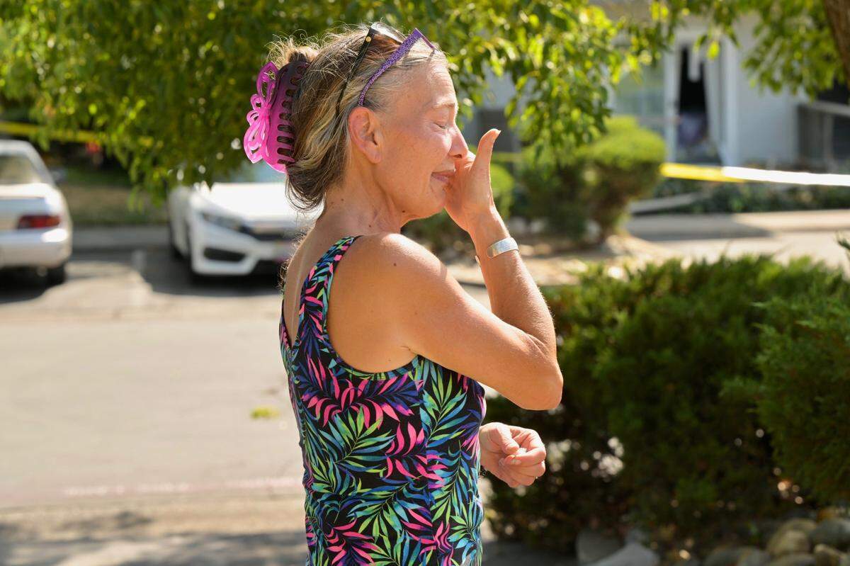 Neighbor Kelly Whitcomb wipes away tears on Friday after three people were found dead inside an Arden Arcade apartment complex following reports of a shooting suspect being holed up inside one of its buildings.