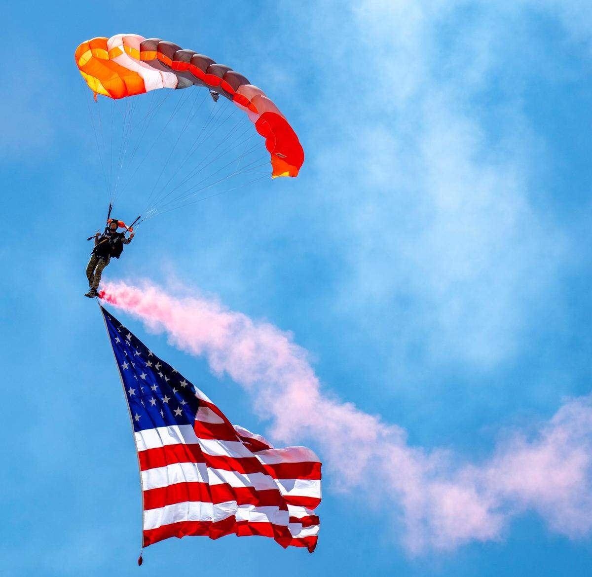 A parachutist from the 418th Flight Test Squadron drifts to the ground with an American flag during the Air & Space Expo at Beale Air Force Base on Saturday, June 7, 2025.