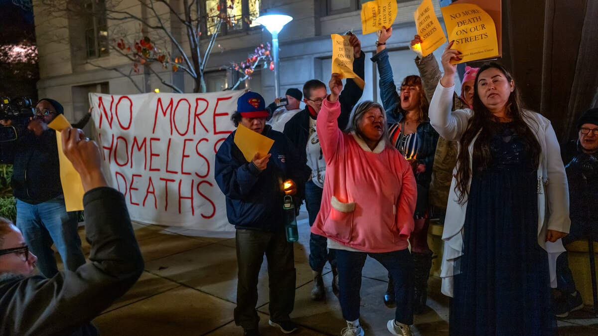 Crystal Sánchez, a la derecha, presidenta de Sacramento Homeless Union, sostiene un volante el jueves 21 de diciembre de 2023, mientras canta "demasiado frío, demasiado calor, no más muertes en nuestras calles" con la comunidad de indigentes en la Décima Conmemoración Anual de las Personas sin Hogar, en el Ayuntamiento, donde se leyeron los nombres de 195 indigentes que murieron en las calles este año. Bob Erlenbusch, director ejecutivo de la Sacramento Regional Coalition to End Homelessness, dijo que creen que esa cifra superará los 200 antes de fin de año.