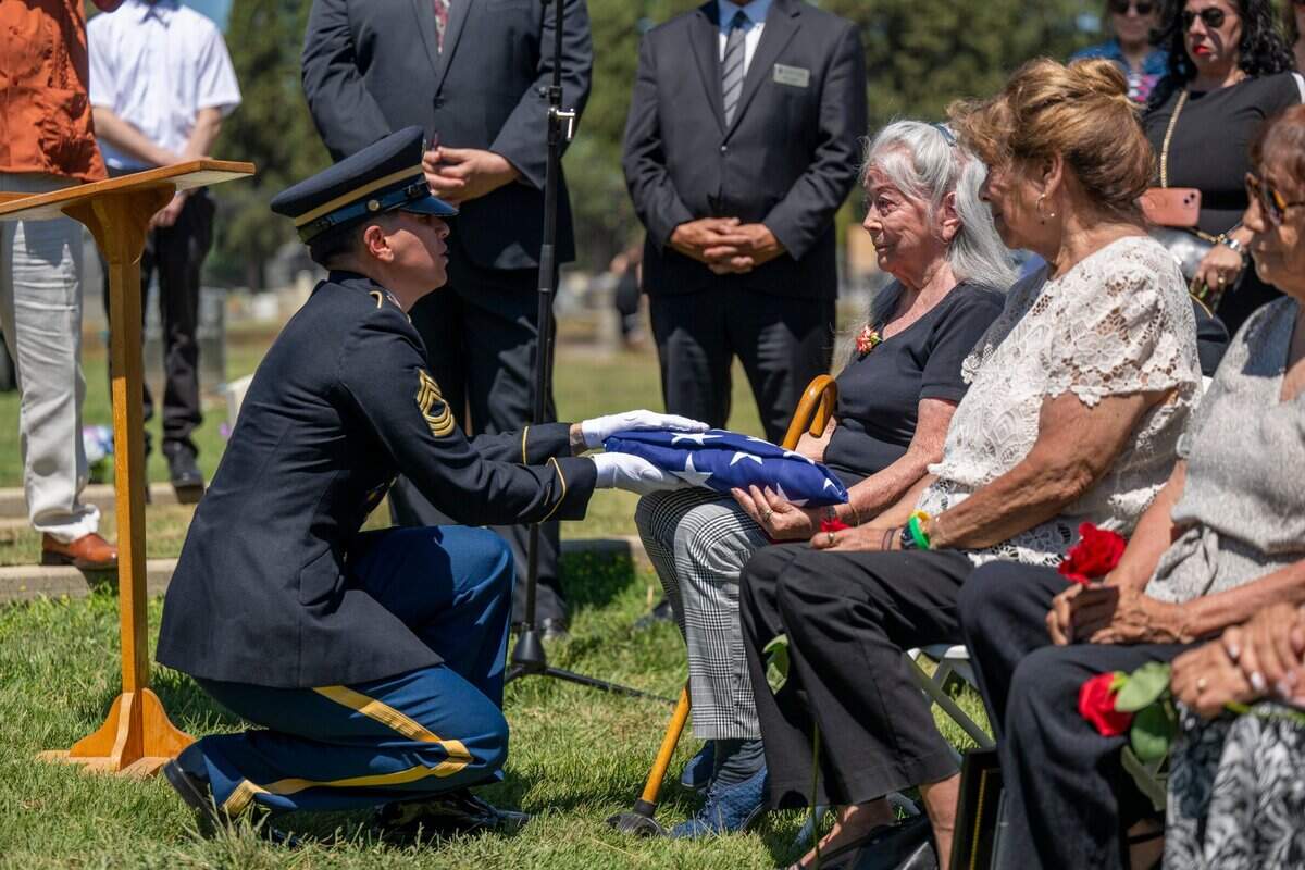 A soldier presents the American flag that draped the casket of Cpl. Albert Estrada, who was killed and missing in action during the Korean War, to his sister Rachel Flores in St. Joseph’s Cemetery in Woodland on Wednesday.