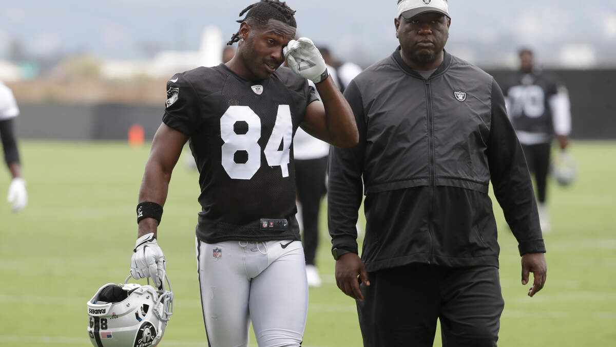 Oakland Raiders’ Antonio Brown, left, walks off the practice field Tuesday, helmet in hand. 