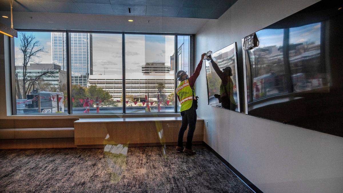 Erik Heerhartz, project director with the state Department of General Services, removes plastic from a video monitor in a large conference room on the third floor of the Natural Resources Headquarters building in downtown Sacramento on Thursday, March 11, 2021. The building has a lot of natural light and the offices and conference rooms have an open concept.