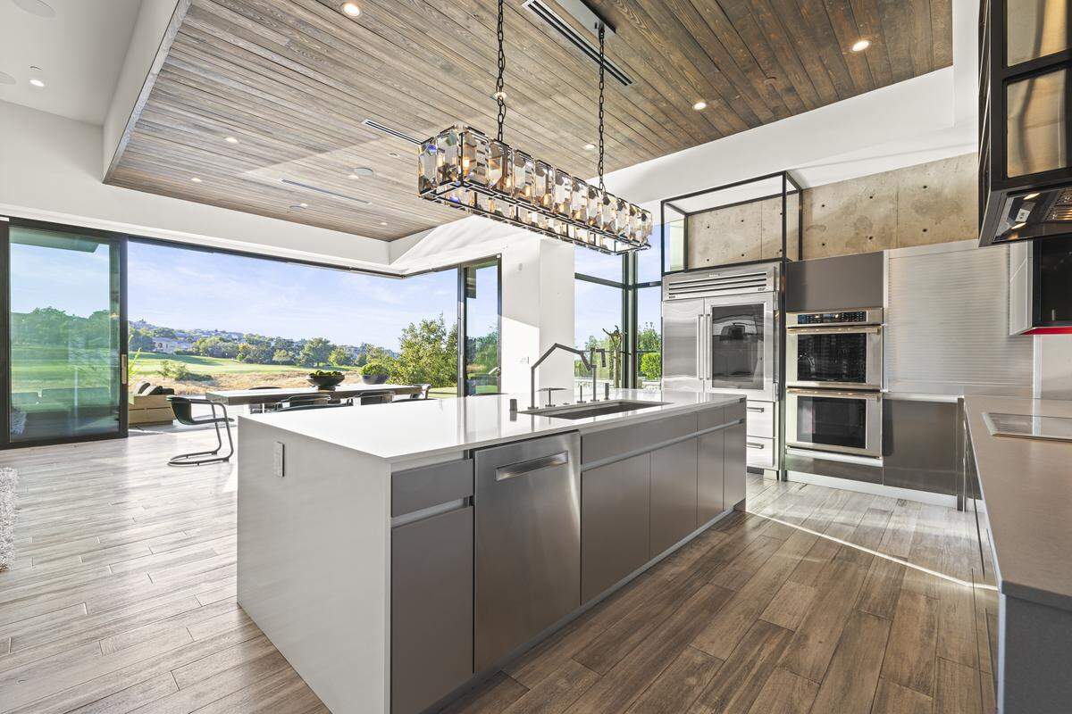 The kitchen area leads through vanishing glass doors to the pool, outdoor kitchen and multiple sitting areas.