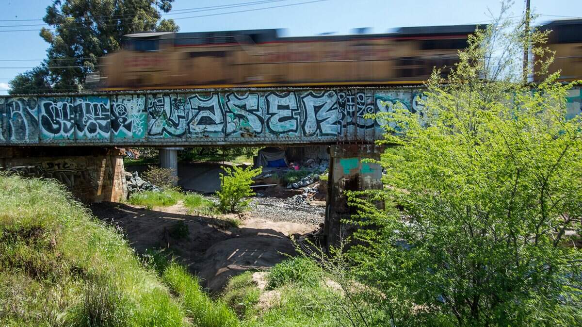 A freight train passes above a homeless encampment near Arcade Creek and Roseville Road.