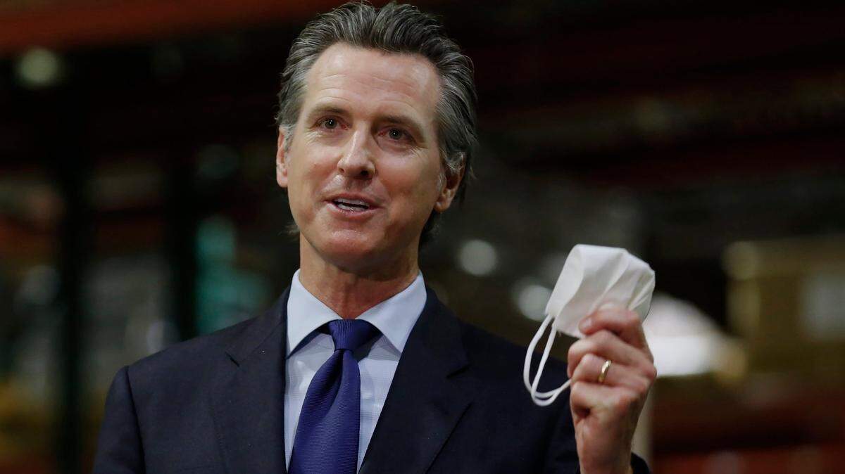 Gov. Gavin Newsom displays a face mask as he urges people to wear them to fight the spread of the coronavirus during a news conference in Rancho Cordova on Friday, June 26, 2020. Newsom said he wants Imperial County in Southern California to reimpose a stay-at-home order amid a surge in positive coronavirus tests.