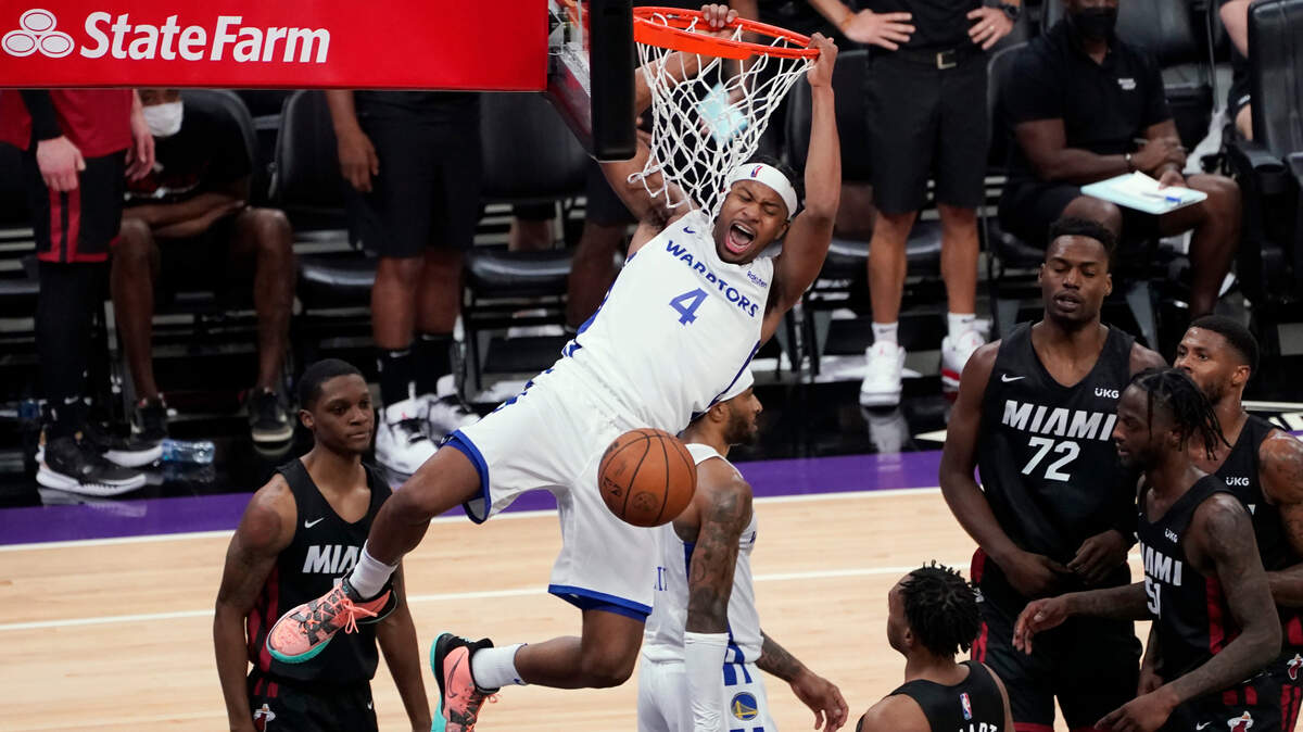 Golden State Warriors guard Moses Moody hangs from the rim after dunking against the Miami Heat during the second half of a California Classic NBA summer league basketball game in Sacramento, Calif., Wednesday, Aug. 4, 2021. (AP Photo/Rich Pedroncelli)