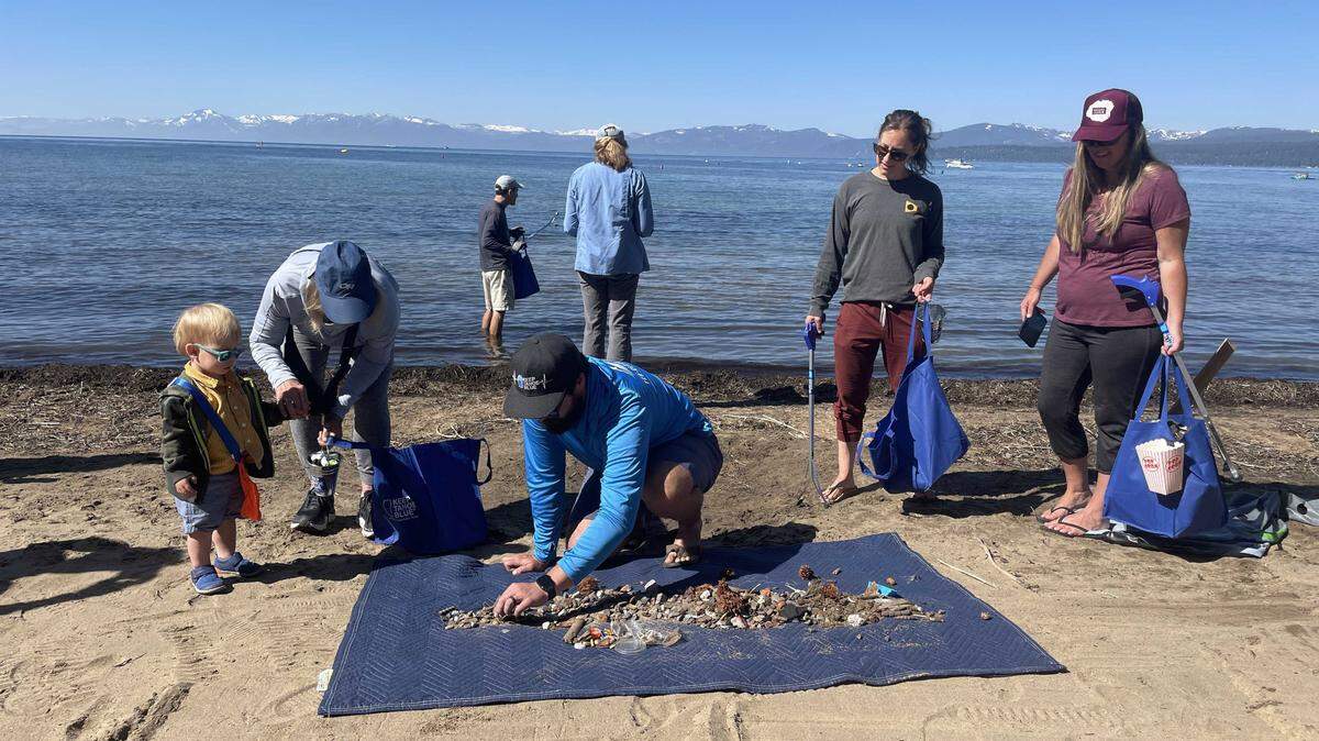 JT Chevallier, center, and volunteers collect debris on Lake Tahoe’s shore at Kings Beach on July 5, 2023. Chevallier helped to deploy BeBot, a beach-cleaning robot from France.