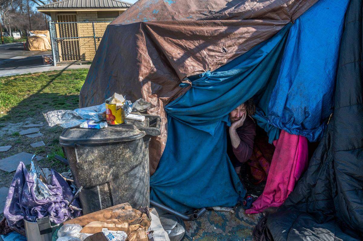 Justin sits in his tent where he lives along X Street next to a park where he has to jump the fence and use the water fountain to get water. A dozen city parks, including those near large homeless encampments, are closed. They are fully functional but the city only opens them for special events.