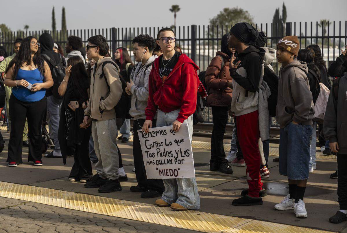 Gianni Miller, a Burbank High School student, holds a sign in Spanish as he waits with other students for the light rail train during a student-led protest against ICE at the state Capitol on Friday. “We have to scream what your parents and mine keep silent because of fear,” the sign reads in Spanish. 