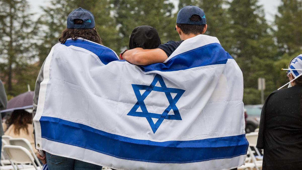 Family members stand together, wrapped in the national flag of Israel as the Chabad Jewish Community Centers from Folsom, Roseville and surrounding areas hold a gathering for unity, prayer and solidarity with Israel.