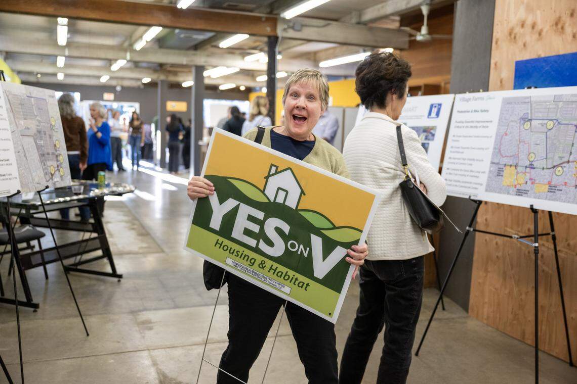 Tracy Tomasky of Davis carries out a Yes on Measure V sign before a kick-off rally for the measure in Davis on Wednesday. The measure would allow a 498-acre development with 1,800 homes on the city's northern boundary to move forward.