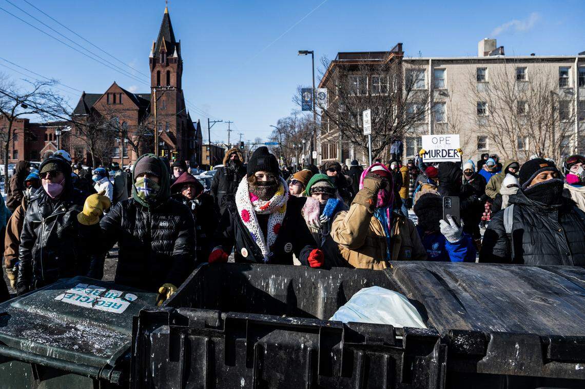 Demonstrators stand behind a barricade of trash bins as they gather near the site of where state and local authorities say a man was shot and killed by federal agents earlier in the morning in Minneapolis, Minnesota, on Saturday. Gov. Gavin Newsom and other prominent California Democrats condemned the shooting.