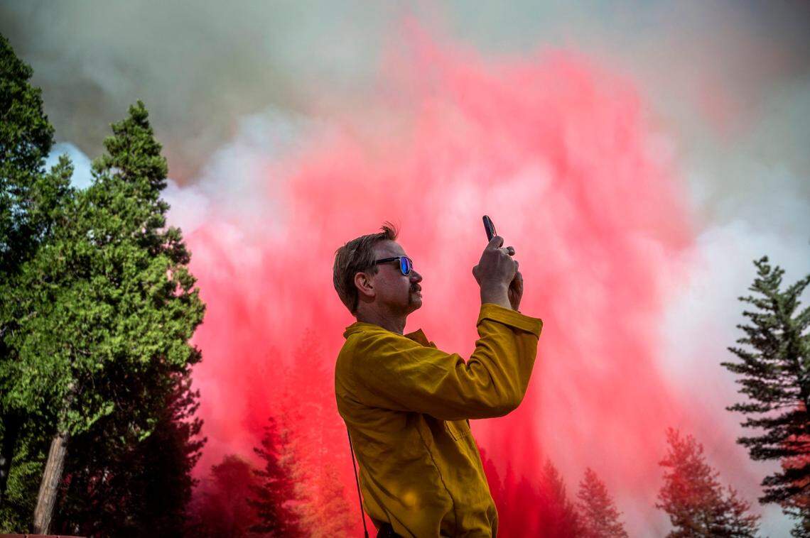 Travis Thane, U.S. Department of Agriculture division chief, takes video of a tanker after it dropped retardant on the Mosquito Fire near Foresthill on Tuesday, Sept. 13, 2022.