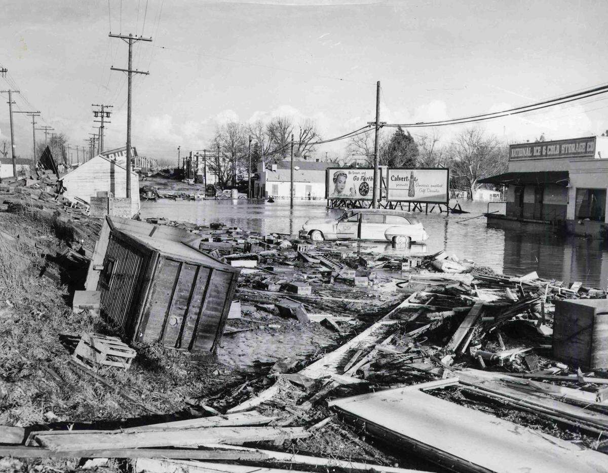Receding flood water in Yuba City leaves debris and wreckage stacked on an embankment, indicating the widespread damage left after the Dec. 24, 1955, flood. 