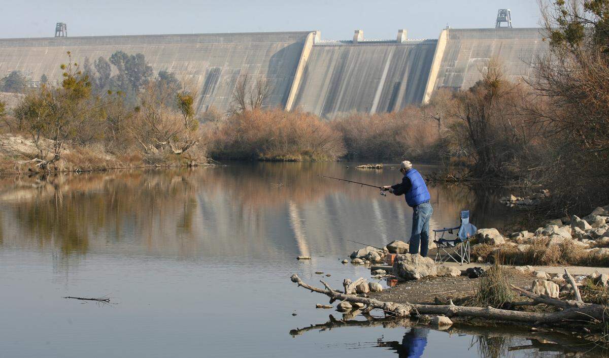 A man fishes in the San Joaquin River below Friant Dam in 2014. The dam has released water for to help salmon spawn downstream since 2006, but much of the water goes missing.