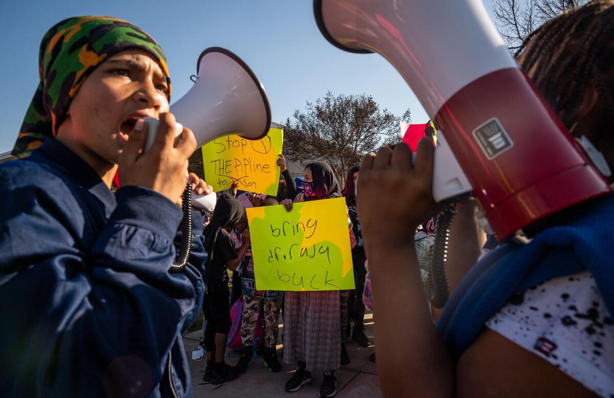 Oakdale School student Sara Omari, 10, center, holds a sign calling for the return of former principal Kadhir Rajagopal, known as Dr. Raja, as fellow students Yousuf Andar, left, 12, and Jameirr, 11, lead chants over megaphones during a walkout protest in North Highlands in 2022. 