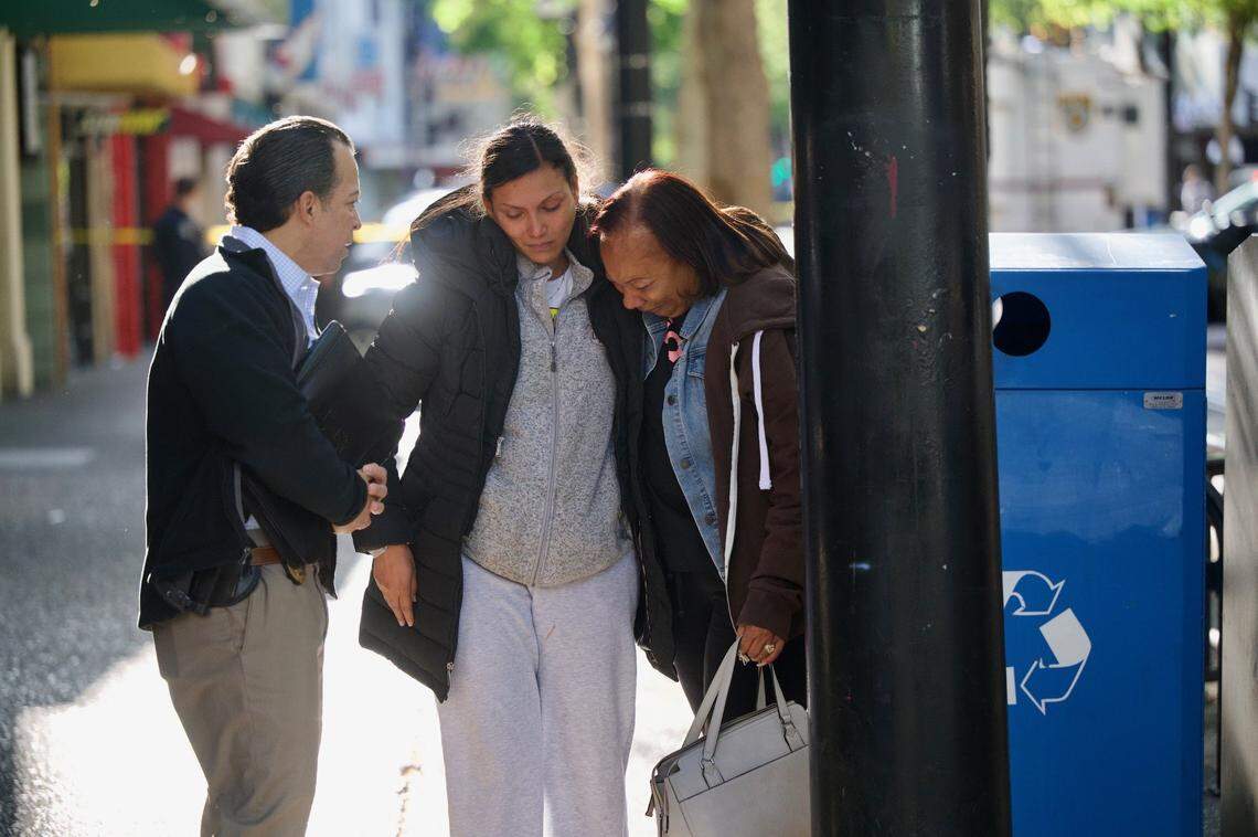 Leticia Harris, center, whose husband Sergio Harris was killed in the mass shooting in downtown Sacramento early Sunday morning, April 3, 2022, speaks with Sacramento police detective Konrad VonSchoech, left, while his mother Pamela Harris sobs.