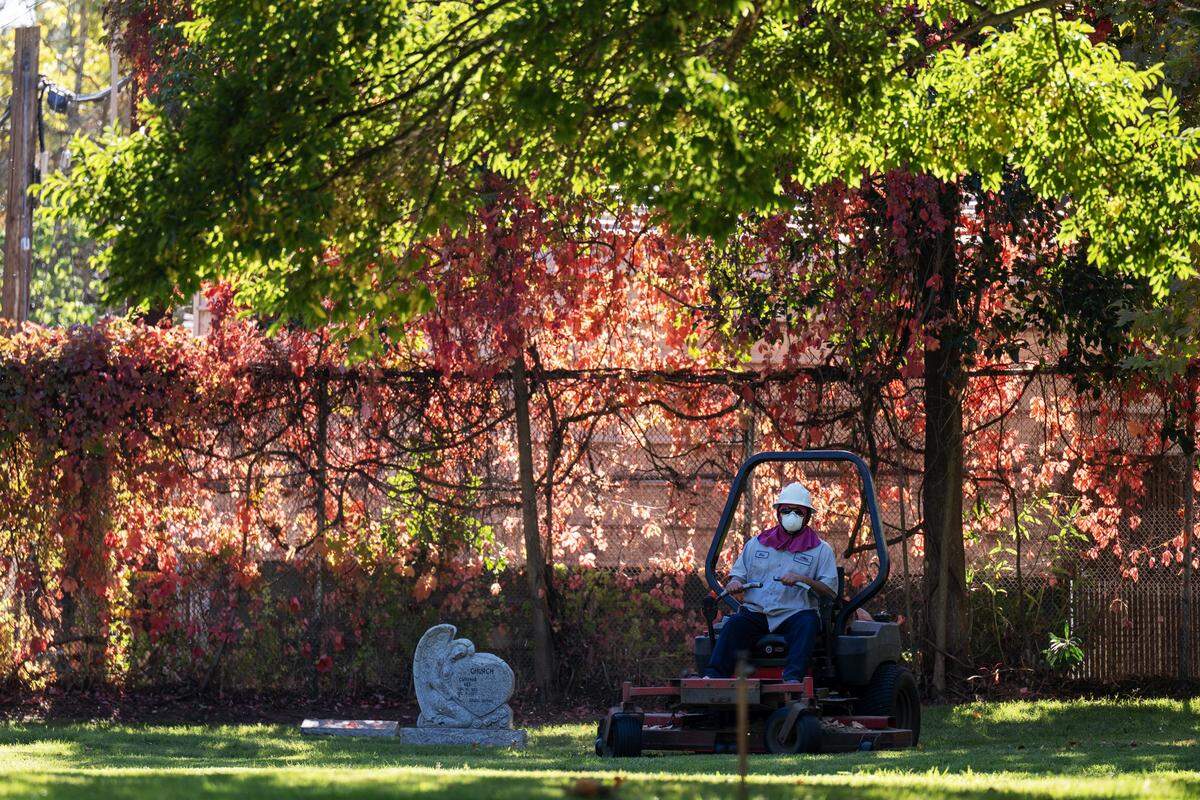 Autumn colors appear at the south end of Odd Fellows Cemetery as Eric Moreno mows the lawn on Tuesday in Sacramento.