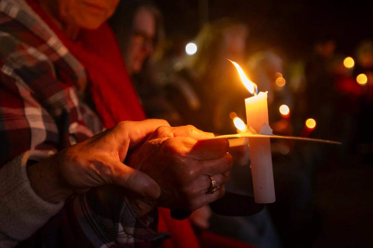Dottie Doyle holds a candle as Claudia Moll holds hands during a prayer at a vigil in downtown Oroville on Friday for the two boys who were injured in a shooting at Feather River Adventist School earlier in the week.