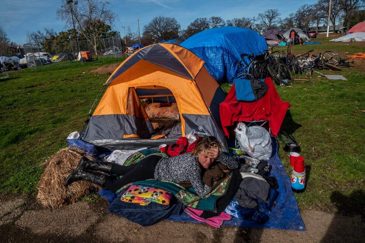 Vikki Emrick, 54, soaks in the sun by her tent in a homeless encampment in Auburn on Jan. 21. “We used to just be on the doorsteps, so this was a great thing that they did,” she said about being allowed to camp on the property. She had no idea when she would have to leave or where she would go. “There are not a lot of places for us to rent.”