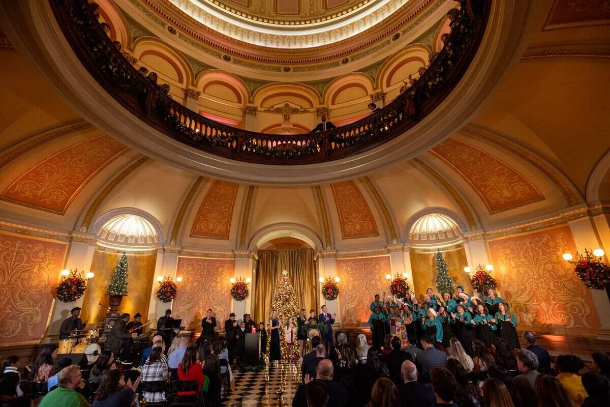 Carter Morris, 9, with his parents Lynne and Karl Morri and sister Samira, listen to the song “Oh Happy Day” sung by the Oakland Interfaith Gospel Choir, with Gov. Gavin Newsom, First Partner Jennifer Siebel Newsom and their children, during the 93rd annual California Capitol tree lighting in the rotunda of the state Capitol in Sacramento on Wednesday, Dec. 11, 2024. Carter Morris was selected by Central Valley Regional Center to light the tree and represent the more than 450,000 Californians with intellectual and developmental disabilities who receive services through the California Department of Developmental Services.