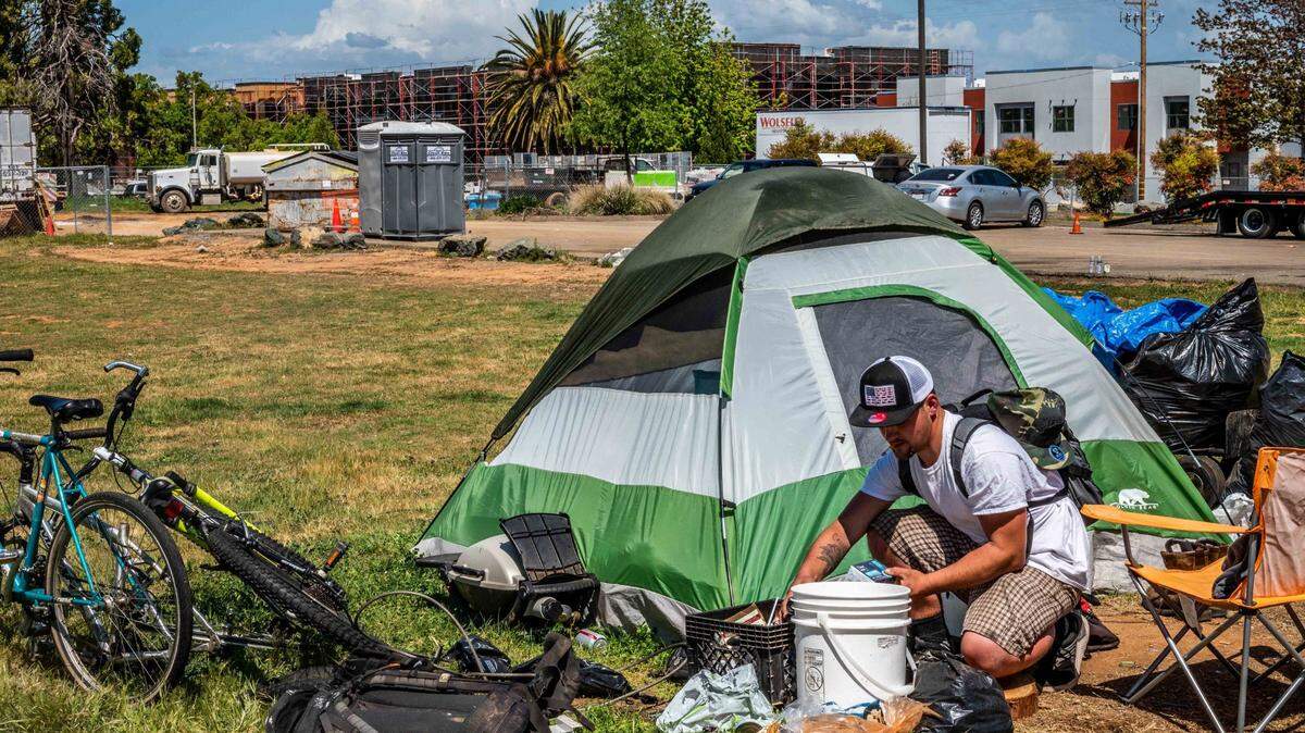 Homeless veteran David Michael Fuchs, 32, cleans up his tent at an encampment across the street from the Mercy affordable housing development in Auburn on Wednesday, April 14, 2021. Roughly 100 homeless individuals live in the area as the county tries to build affordable housing.