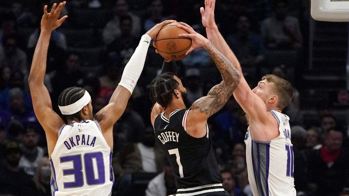 Los Angeles Clippers guard Amir Coffey, center, has his shot blocked by Sacramento Kings forward KZ Okpala, left, as forward Domantas Sabonis defends during the second half of an NBA basketball game Saturday, Dec. 3, 2022, in Los Angeles. (AP Photo/Mark J. Terrill)