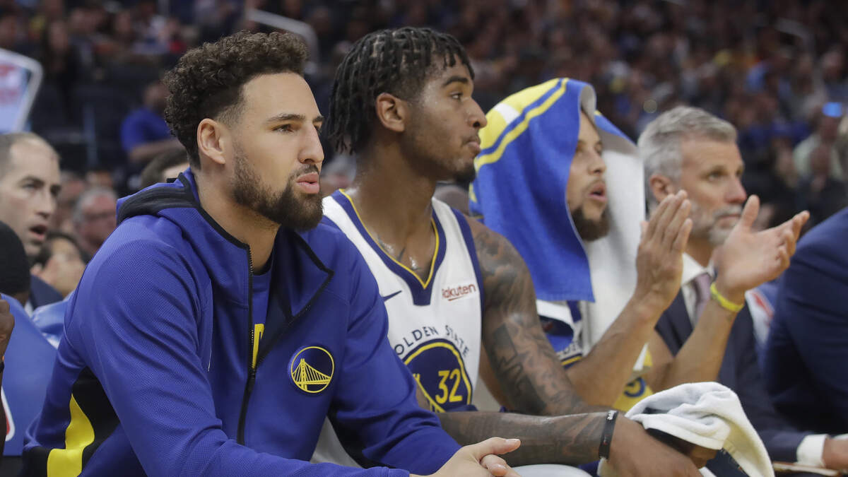 Marquese Chriss, center, sits in between Golden State Warriors teammates Klay Thompson, left, and Stephen Curry during a preseason game against the Los Angeles Lakers on Saturday in San Francisco. Chriss, a Pleasant Grove High graduate, is trying to earn a spot on the team’s regular-season roster.