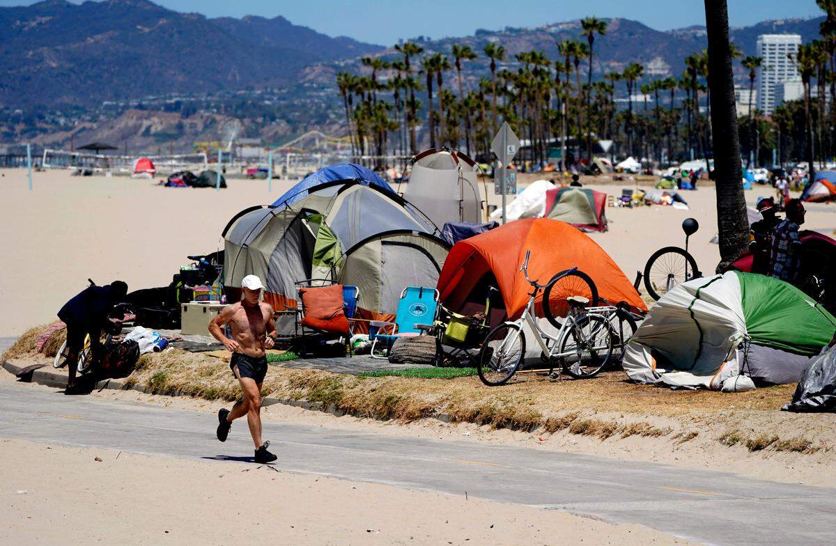 A jogger runs past a homeless encampment in the Venice Beach neighborhood of Los Angeles in 2021.