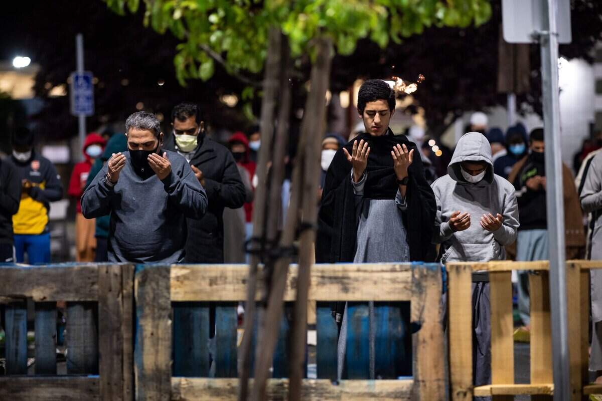 Khaled Hamid, left, of Sacramento, and 17-year-old Vokil Alla Nur, of Elk Grove, stand among distanced and mask-wearing worshippers in a sectioned off part of the parking lot at Masjid Annur Islamic Center in south Sacramento on Tuesday during Taraweeh prayers after the first day of fasting for Muslims during Ramadan.