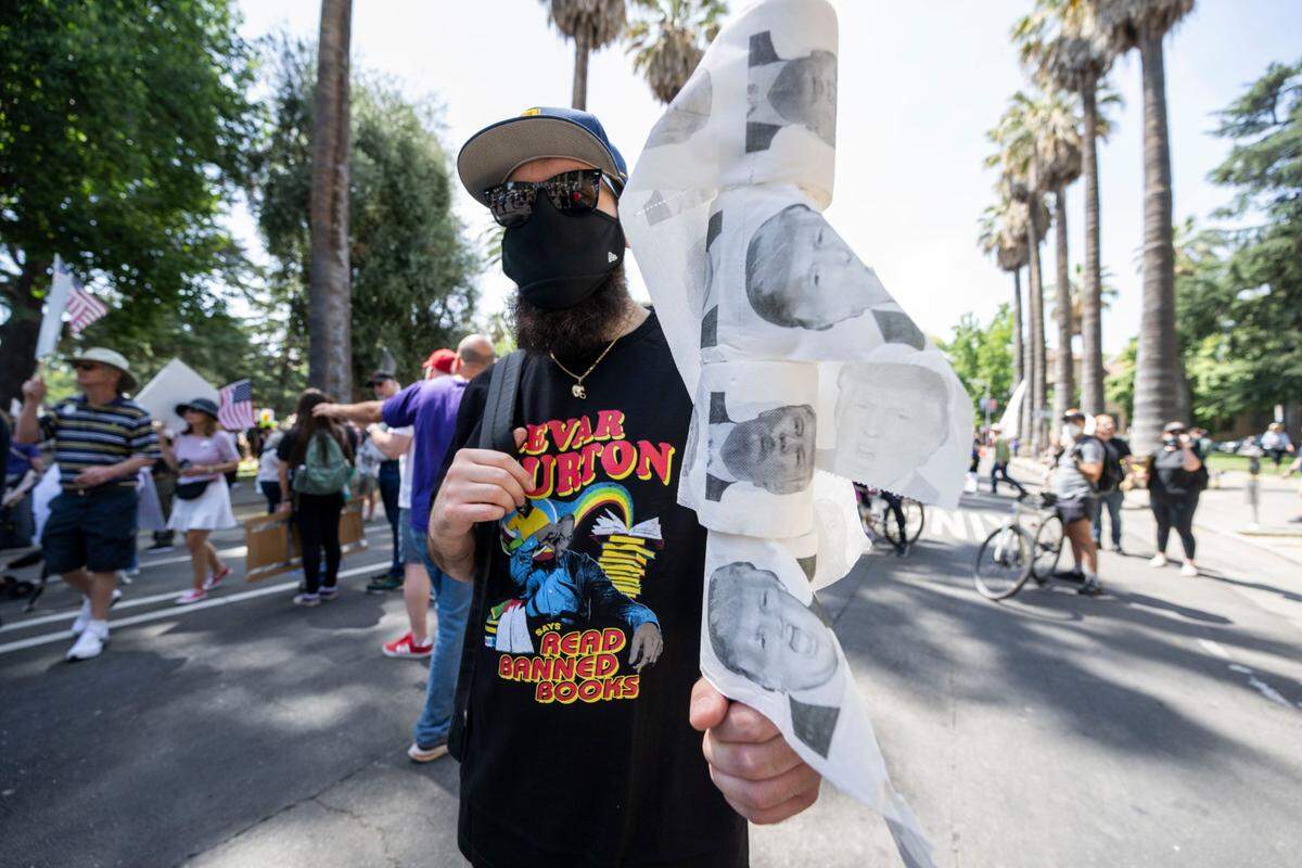 Donovan Parker, of Sacramento, holds rolls of toilet paper with images of President Donald Trump during the “No Kings” protest at the state Capitol on Saturday.