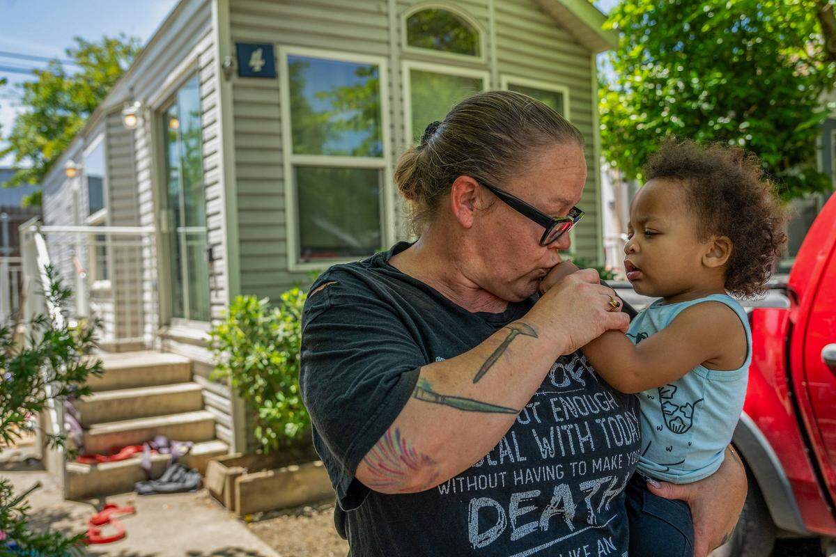 Amber Criswell, 46, kisses her youngest grandson Knowledge McArn, 2, on Tuesday outside a city-funded Sacramento cottage where she has been living with her three grandchildren since 2023. The city has changed the program, and the family is unsure where they will go. 