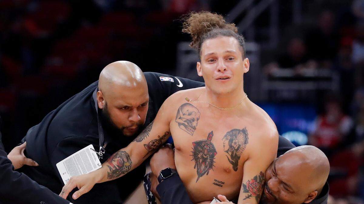 Security employees tackle a spectator who ran onto the court and removed most of his clothes during the second half of an NBA basketball game between the Sacramento Kings and Houston Rockets on Friday, April 1, 2022, in Houston. (AP Photo/Michael Wyke)