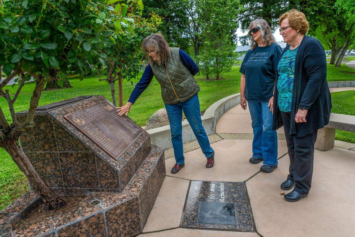 Survivor Jan Roberts-Haydon touches the names of those who died and survived the 1976 Yuba City High School bus crash as she stands beside fellow survivors Christy Young Estabrook, center, and Donna Peacock Sorenson, right, at a memorial in Yuba City on Monday. Of the 53 on board, 29 died and 24 survived.