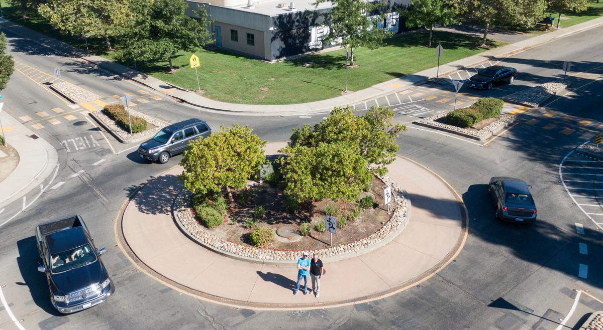 Safer streets advocates Matt Malkin, left, and Jerry Champa stand for a picture in the roundabout at the intersection of Orchard Lane and West River Drive in Sacramento’s South Natomas neighborhood, near Leroy Greene Academy.