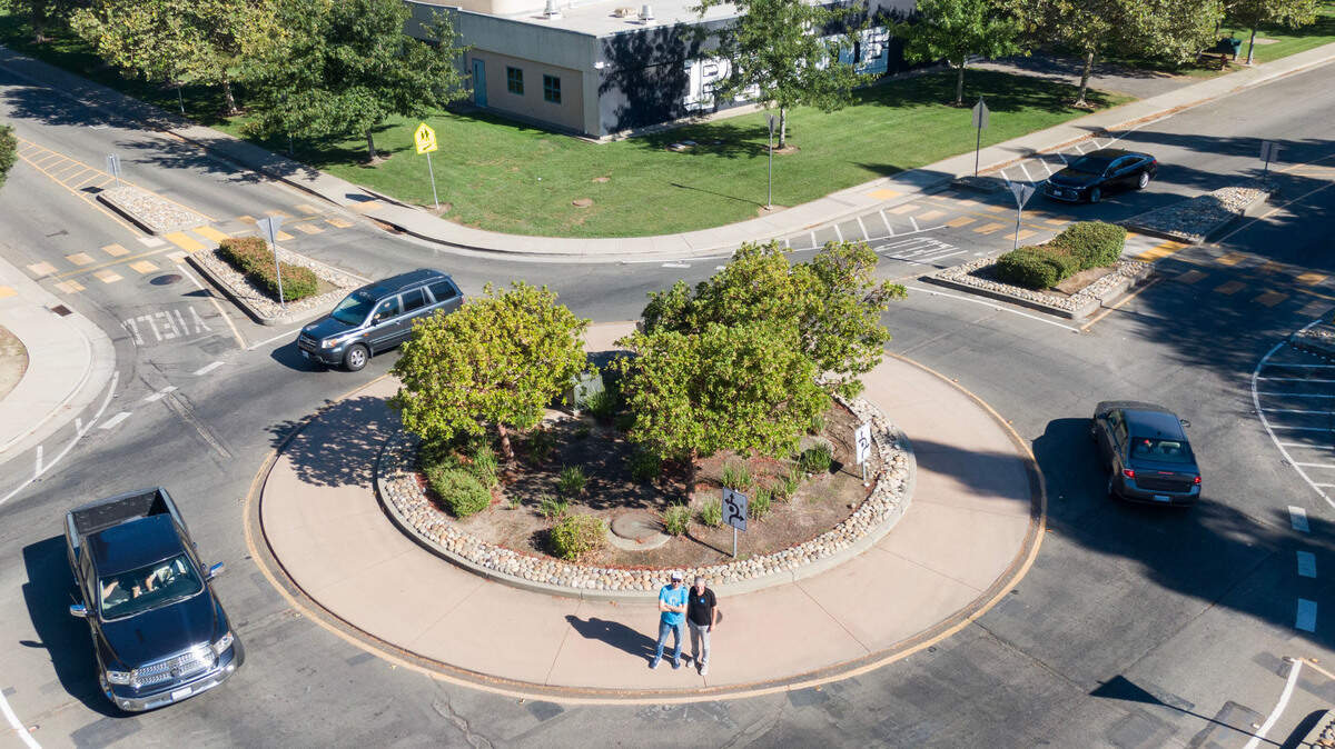 Safer streets advocates Matt Malkin, left, and Jerry Champa stand for a picture Monday, Aug. 19, 2024, in the roundabout at the intersection of Orchard Lane and West River Drive in Sacramento’s South Natomas neighborhood, near Leroy Greene Academy.