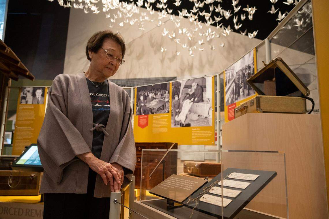 Christine Umeda stands earlier this month next to the numbered tags, on display at the new “Uprooted: An American Story” exhibition, that her husband’s family had to wear when they we sent to the incarceration camps. “This is the power of the presidency, and although is was misguided it did lead to a really unconstitutional period in our time, where we were unjustly incarcerated,” she said.