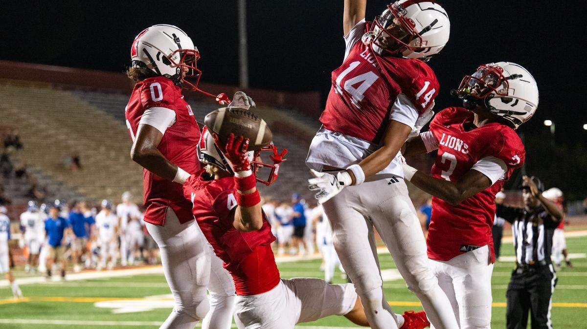The McClatchy Lions' Jake Ferris (4) celebrates a touchdown with teammates at the end of the first half against the Davis Blue Devils on Friday at Hughes Stadium in Sacramento. 