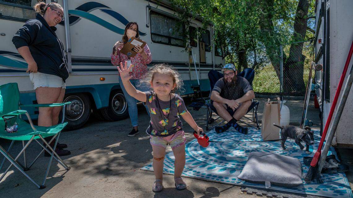 Cillían Coyle, 2, is happy to greet people in April as she holds a leash for her new puppy Maverick while her parents April Crowell, left, and David Coyle, right, get registered at the Safe Ground encampment near Miller Park. The city is moving ahead with a similar facility on Meadowview Road.