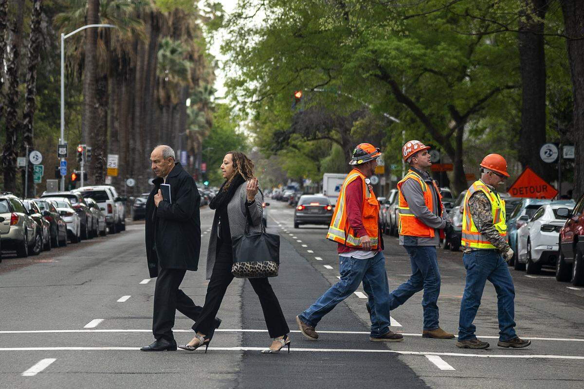Groups of people walk less that 6 feet apart as they cross N Street at 11th Street during the coronavirus outbreak on Wednesday, March 18, 2020 in Sacramento.