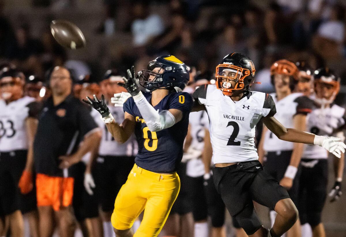 Oak Ridge Trojan wide receiver Sebastian Sutton (0) pulls in a deep pass from Oak Ridge Trojan quarterback Maddox Varella (4), as Vacaville Bulldog Jemeir Buckner (2) interferes but can’t prevent the play, during the second quarter of the high school varsity football game Friday at Oak Ridge High School in El Dorado Hills.