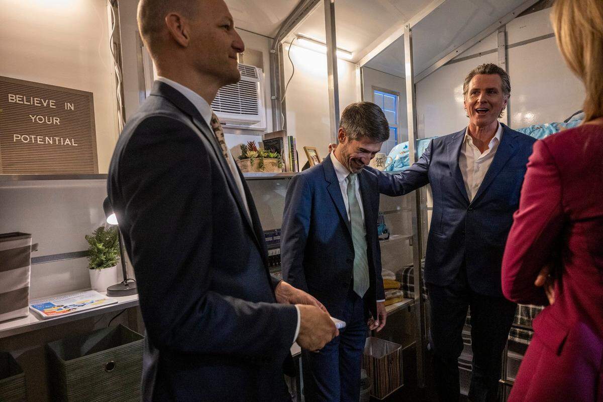 Gov. Gavin Newsom, right, San José Mayor Matt Mahan, center, and Assemblymember Kevin McCarty, left, tour a tiny home Thursday after Newsom announced the state will have 1,200 tiny homes built and delivered throughout California in an effort to help house the homeless population.