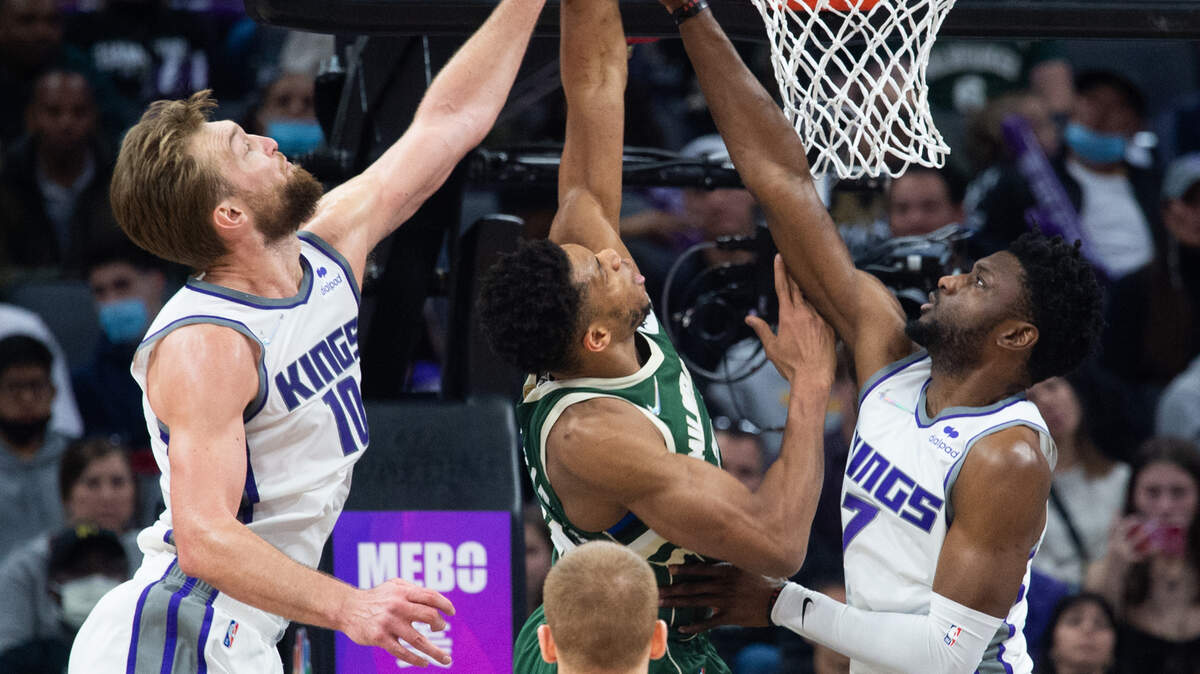 Milwaukee Bucks forward Giannis Antetokounmpo (34) scores a basket defended by Sacramento Kings forward Domantas Sabonis (10) and Sacramento Kings forward Chimezie Metu (7) during a game at the Golden 1 Center in Sacramento, Wednesday, March 16, 2022.