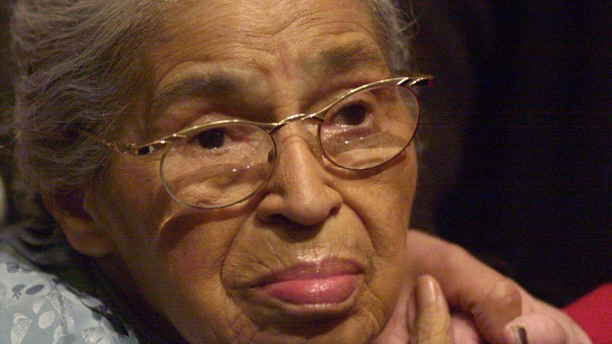 Civil rights pioneer Rosa Parks holds the hand of a well-wisher at a ceremony Dec. 1, 2001 to honor the 46th anniversary of her arrest for civil disobedience.