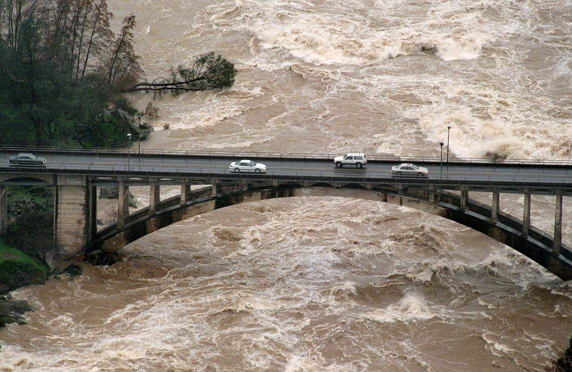 The American River rages under the Rainbow Bridge in Folsom on Jan. 2, 1997.
