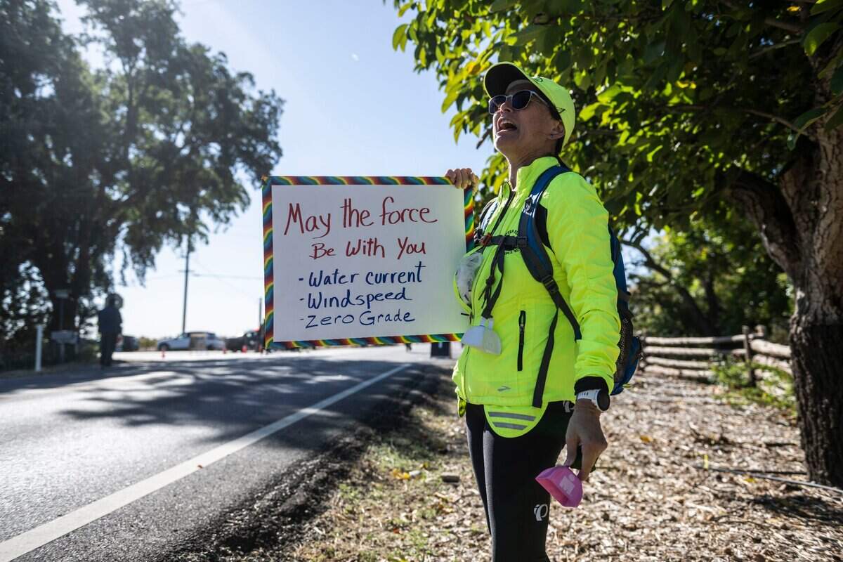 Lisa Barry cheers on athletes competing in the Ironman California as they complete the bicycle leg of the triathlon on Jefferson Boulevard in West Sacramento on Sunday, Oct. 23, 2022.