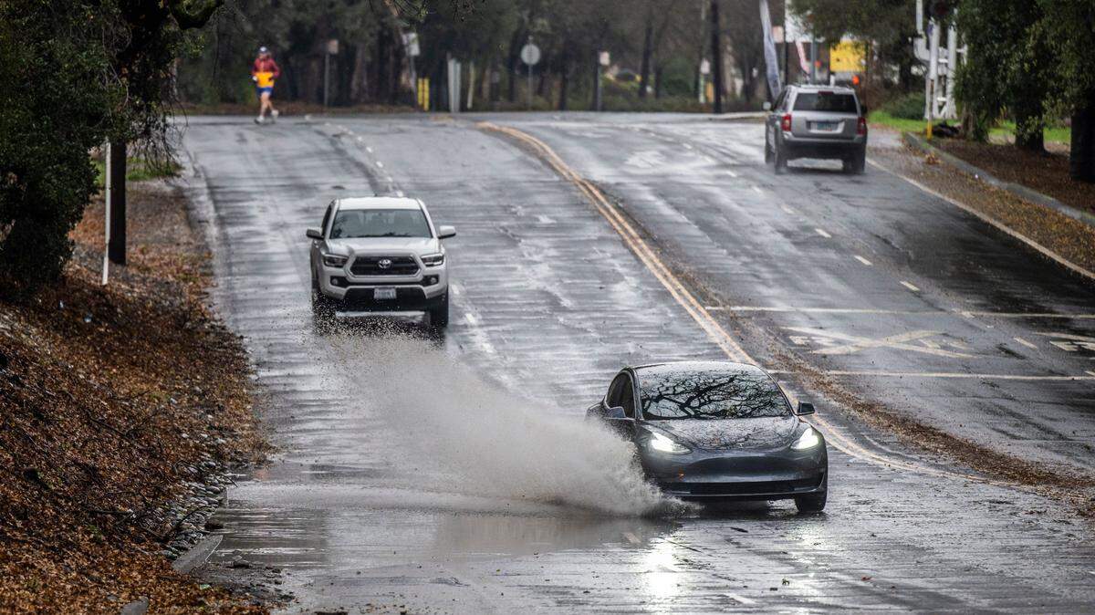 A Tesla crosses a flooded section of Sutterville Road in Sacramento on Tuesday, Dec. 27, 2022. The city received 0.85 inches of rain Tuesday.