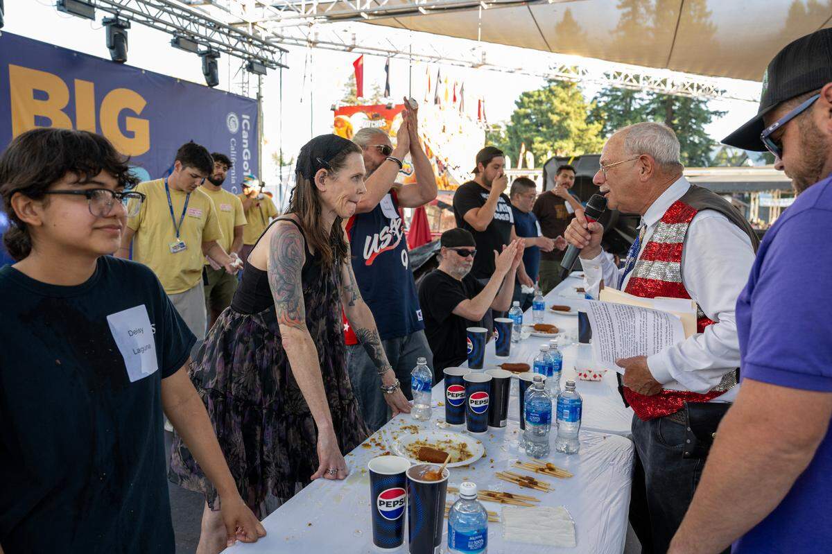 Event MC Dennis Forel, right, looks at contestant Molly Schuyler of Maryland after counting she had consumed 22 1/4 corndogs to win a corndog eating contest semifinal at the California State Fair in Sacramento on Friday.
